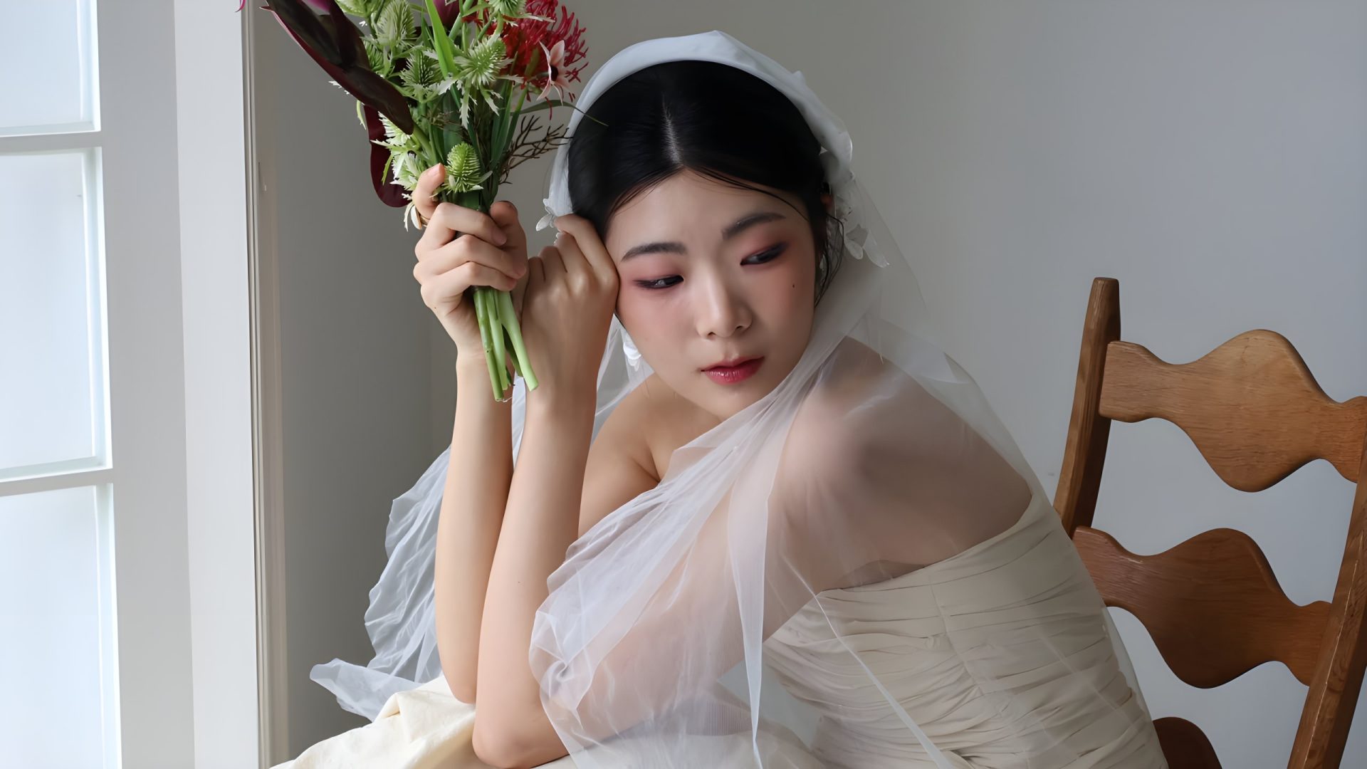Mariée près d'une fenêtre, bouquet à la main